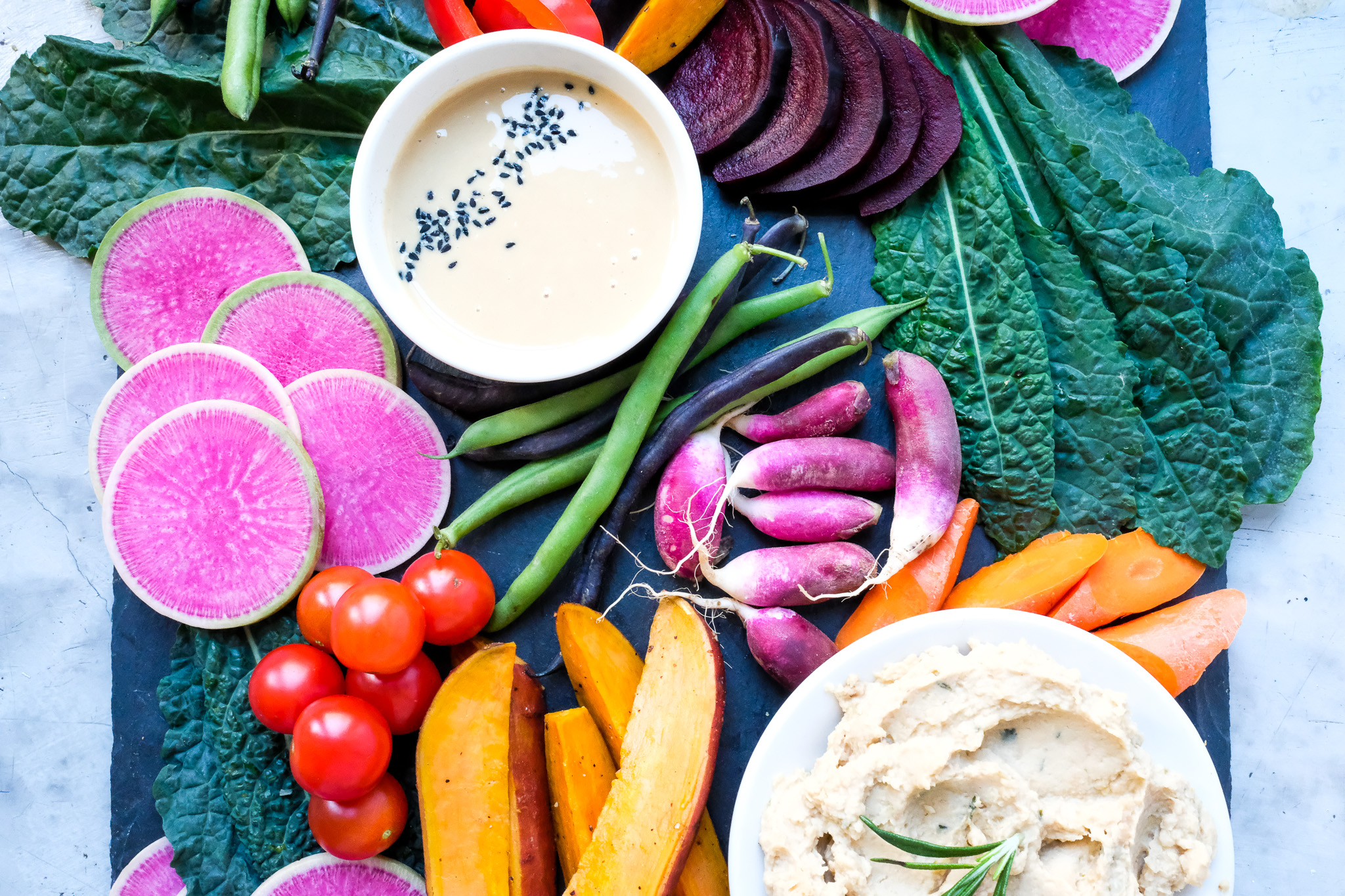 Tzatziki sauce in a bowl surrounded by vegetables