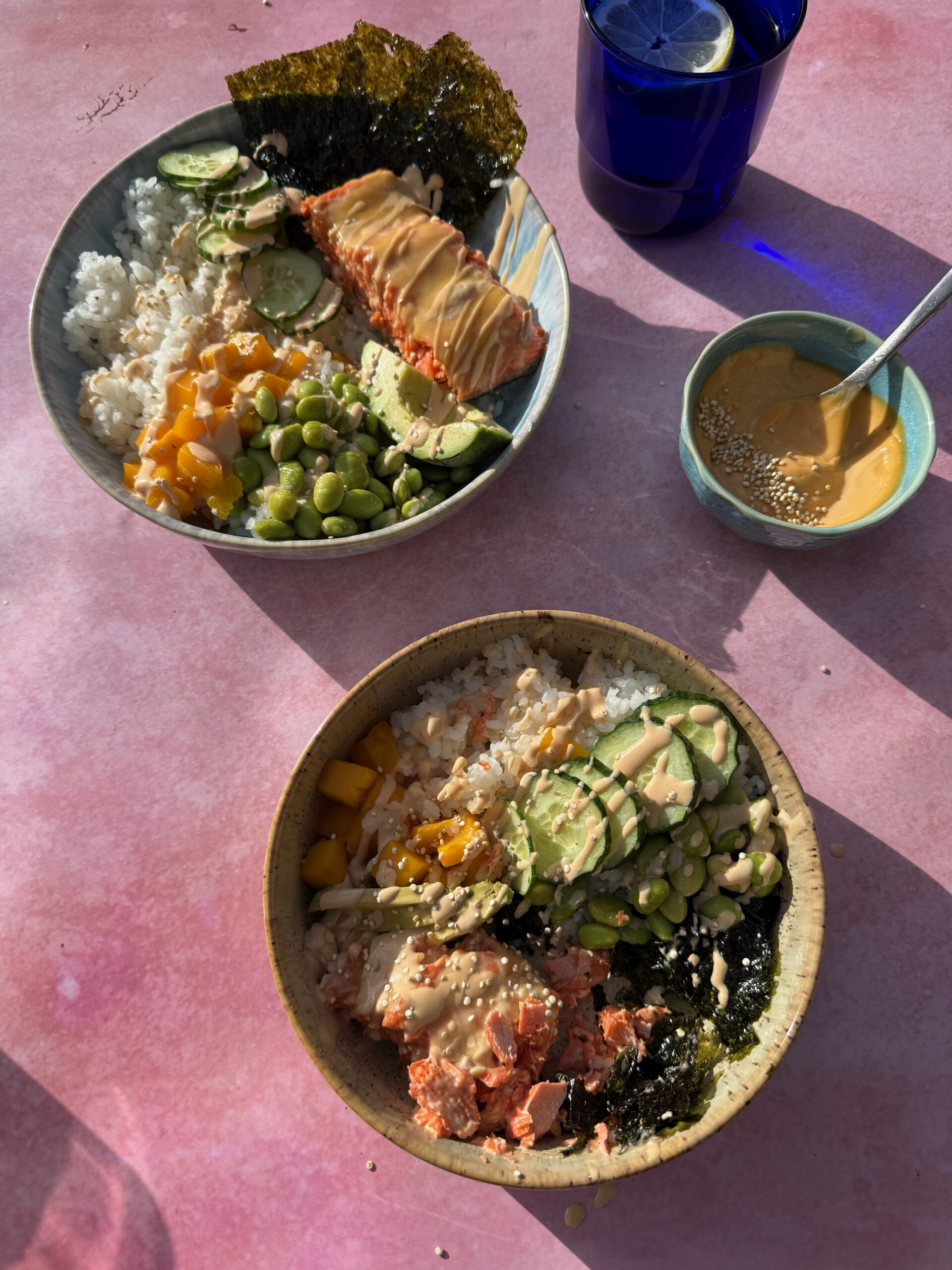 Spicy Mayo on a piece of cooked salmon which is in a bowl of rice, avocados and nori